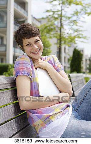 Stock Image - Young woman embracing iPad on a bench . Fotosearch