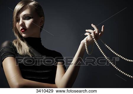 Stock Photo - Young woman holding pearl necklace in her hand . Fotosearch