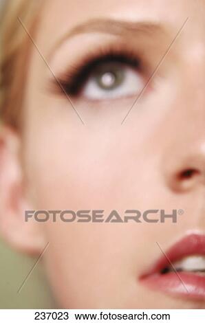 Stock Image - Young woman looking up, close-up . Fotosearch