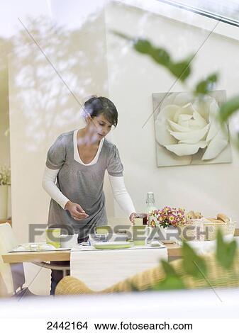 Picture - Young woman placing breakfast at table . Fotosearch