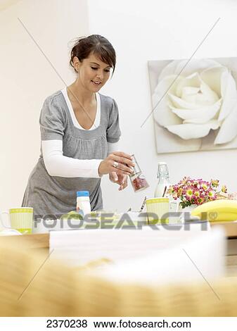 Stock Photo - Young woman placing breakfast on table . Fotosearch
