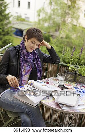 Young woman reading magazine on balcony View Large Photo Image Stock Image - Young woman reading magazine on balcony . Fotosearch
