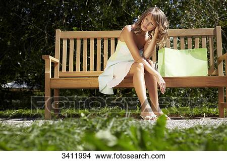 Young woman resting on a park bench View Large Photo Image Picture - Young woman resting on a park bench . Fotosearch