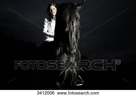 Young woman riding on a black horse View Large Photo Image Stock Photograph - Young woman riding on a black horse . Fotosearch