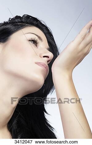 Stock Photo - Young woman smelling perfume at wrist, ow angle view . Fotosearch