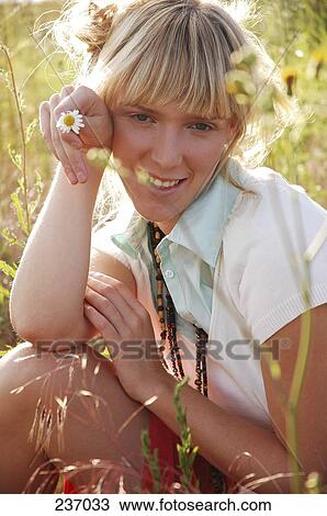 Stock Image - Young woman squatting in meadow . Fotosearch