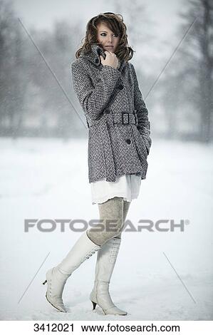 Stock Image - Young woman standing with poncho in snow . Fotosearch