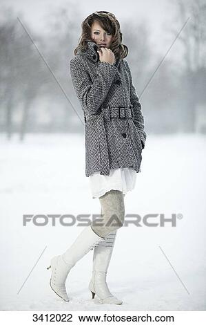 Stock Image - Young woman standing with poncho in snow . Fotosearch
