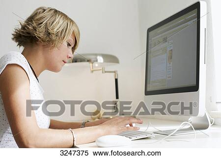 Stock Photography - Young woman using desktop computer, side view . Fotosearch