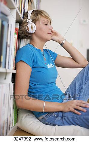 Stock Image - Young woman using headphones, side view . Fotosearch