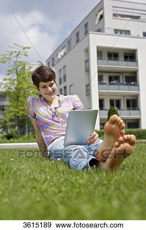 Young woman using iPad in grass View Large Photo Image Stock Photo - Young woman using iPad in grass . Fotosearch