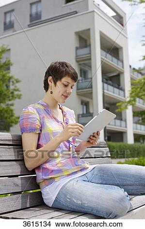 Young woman using iPad on a bench View Large Photo Image Picture - Young woman using iPad on a bench . Fotosearch