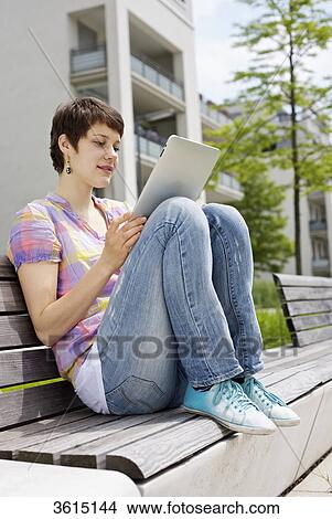 Picture - Young woman using iPad on a bench . Fotosearch