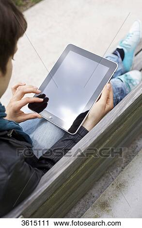 Young woman using iPad on a bench View Large Photo Image Stock Image - Young woman using iPad on a bench . Fotosearch