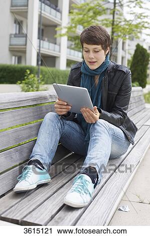 Young woman using iPad on a bench View Large Photo Image Stock Image - Young woman using iPad on a bench . Fotosearch