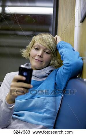 Young woman using mobile phone in city train, front view View Large Photo Image Stock Image - Young woman using mobile phone in city train, front view . Fotosearch