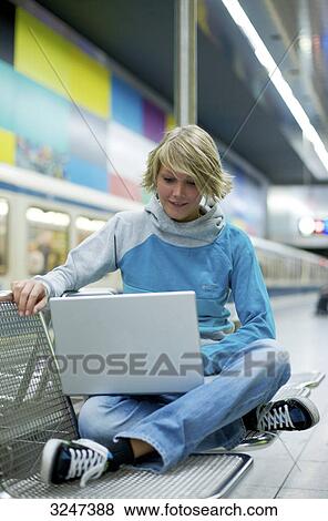 Young woman using notebook at city train station, front view View Large Photo Image Stock Photo - Young woman using notebook at city train station, front view . Fotosearch