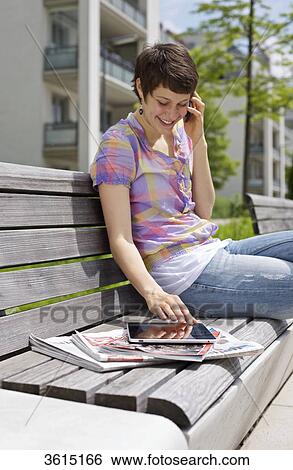 Young woman with cell phone and iPad on a bench View Large Photo Image Stock Photograph - Young woman with cell phone and iPad on a bench . Fotosearch