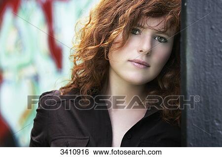 Stock Photograph - Young woman with red hair looking at camera, portrait . Fotosearch