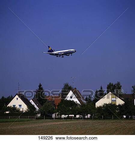 Stock Photograph - Airplane flying over houses, Munich, Bavaria, Germany . Fotosearch