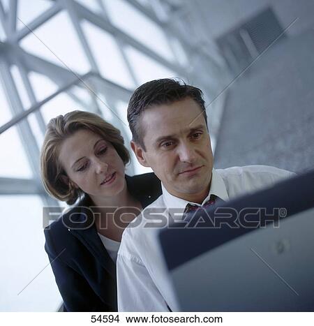 Businessman and businesswoman looking at laptop View Large Photo Image Picture - Businessman and businesswoman looking at laptop . Fotosearch