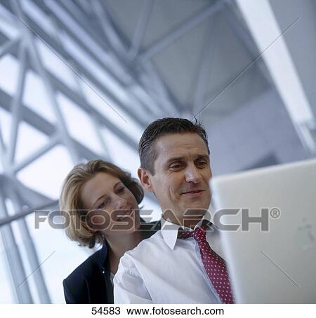 Stock Image - Businessman and businesswoman looking at laptop . Fotosearch