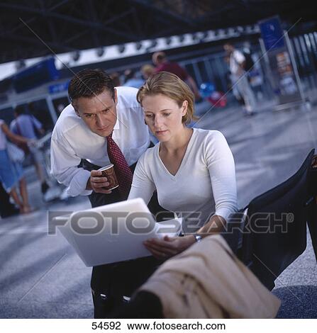 Stock Image - Businessman and businesswoman looking at laptop . Fotosearch