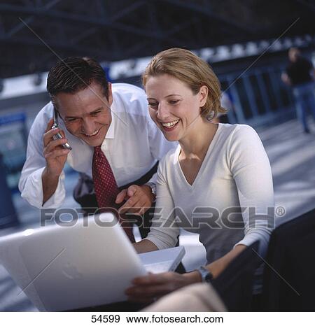 Stock Photo - Businessman and businesswoman looking at laptop and smiling . Fotosearch