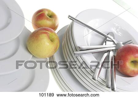 Stock Photo - Close-up of apple and table knives on stack of plates . Fotosearch