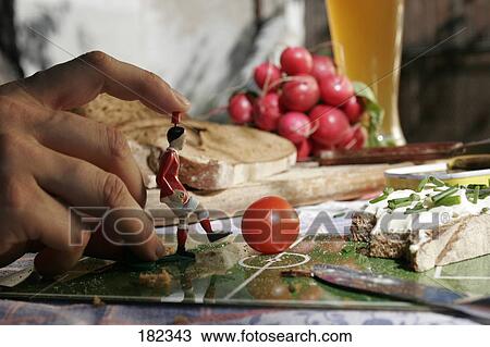 Stock Image - Close-up of figurine of soccer player kicking tomato . Fotosearch