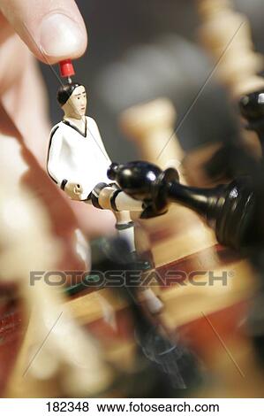 Stock Photo - Close-up of figurine of soccer player kicking chess piece . Fotosearch