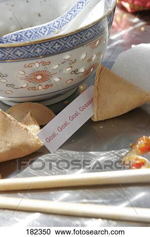 Stock Image - Close-up of Goal fortune sticking out of fortune cookie . Fotosearch