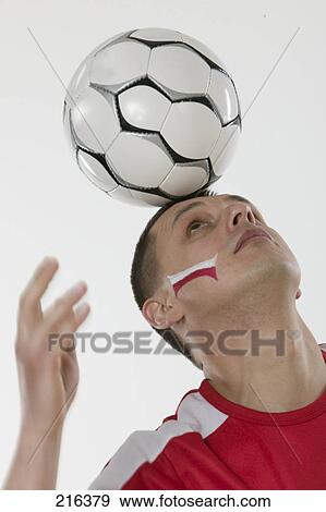 Stock Photo - Close-up of man balancing soccer ball on his head . Fotosearch