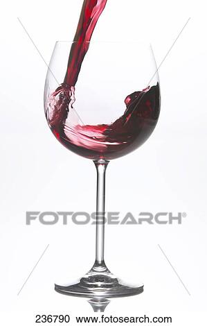 Stock Image - Close-up of red wine being poured into wine glass . Fotosearch