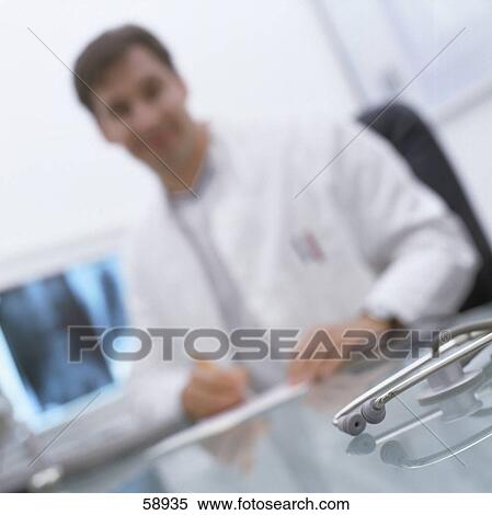 Stock Photography - Close-up of stethoscope on table with male doctor in background . Fotosearch