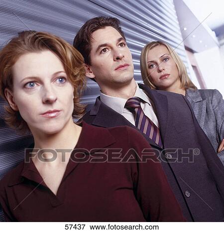 Close-up of two businesswomen and businessman standing in row View Large Photo Image Stock Photo - Close-up of two businesswomen and businessman standing in row . Fotosearch