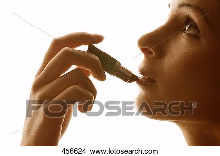 Close-up of young woman applying lipstick View Large Photo Image Picture - Close-up of young woman applying lipstick . Fotosearch
