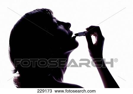 Stock Image - Close-up of young woman applying lipstick . Fotosearch