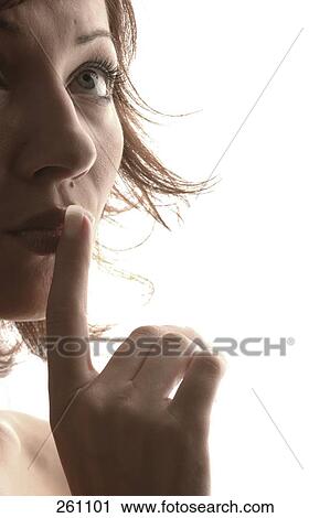Stock Image - Close-up of young woman with her finger on her lips . Fotosearch