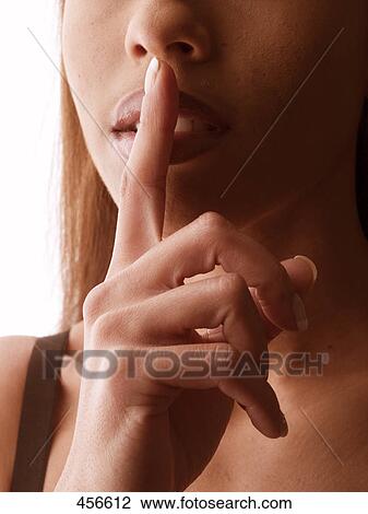 Stock Image - Close-up of young woman with her finger on her lips . Fotosearch