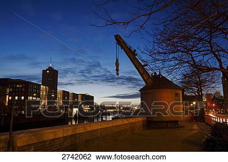 Stock Image - Crane on riverside at dusk, Hamburg, Germany . Fotosearch