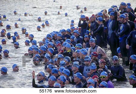 Stock Photograph - Crowd of triathletics swimming in water for triathlon . Fotosearch