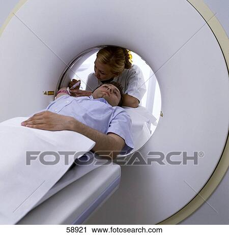 Stock Image - Female doctor giving injection to patient in MRI machine . Fotosearch