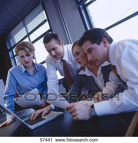 Four businesspeople looking at a laptop in a meeting  View Large Photo Image Stock Image - Four businesspeople looking at a laptop in a meeting . Fotosearch