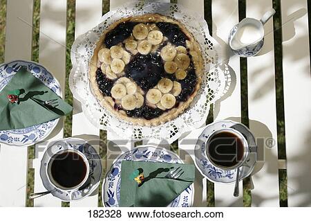 Stock Photo - High angle view of fruit cake and cups of black coffee on table . Fotosearch