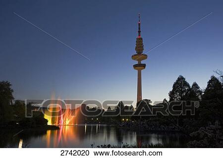 Lit up fountains near telecommunication tower against dusky sky, Hamburg, Germany View Large Photo Image Stock Image - Lit up fountains near telecommunication tower against dusky sky, Hamburg, Germany . Fotosearch