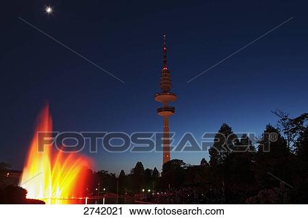 Lit up fountains near telecommunication tower against dusky sky, Hamburg, Germany View Large Photo Image Stock Image - Lit up fountains near telecommunication tower against dusky sky, Hamburg, Germany . Fotosearch
