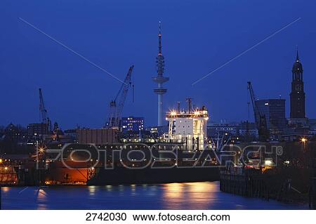 Stock Image - Lit up port at dusk, Hamburg, Germany . Fotosearch