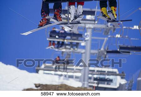 Stock Photo - Low section view of skiers sitting on ski lift . Fotosearch