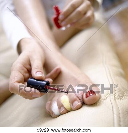 Stock Photo - Low section view of young woman painting foot nails . Fotosearch